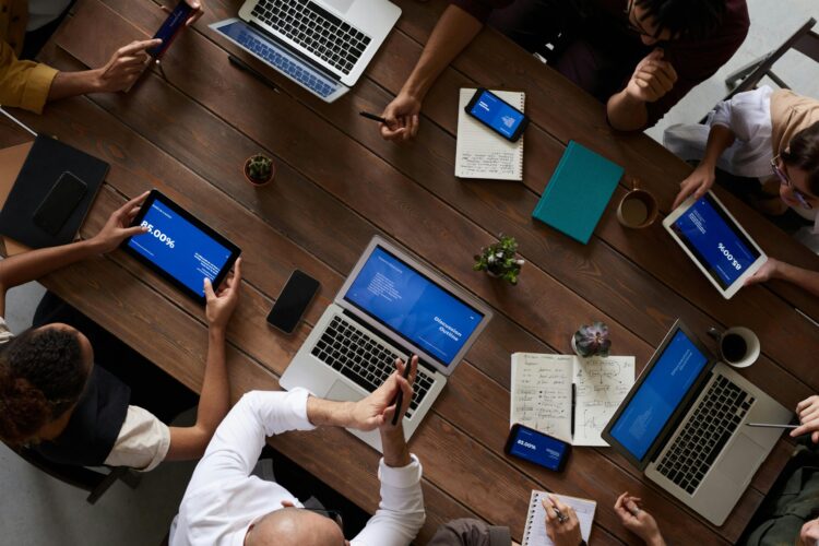 Group of business people sitting around a table with laptops and tablets