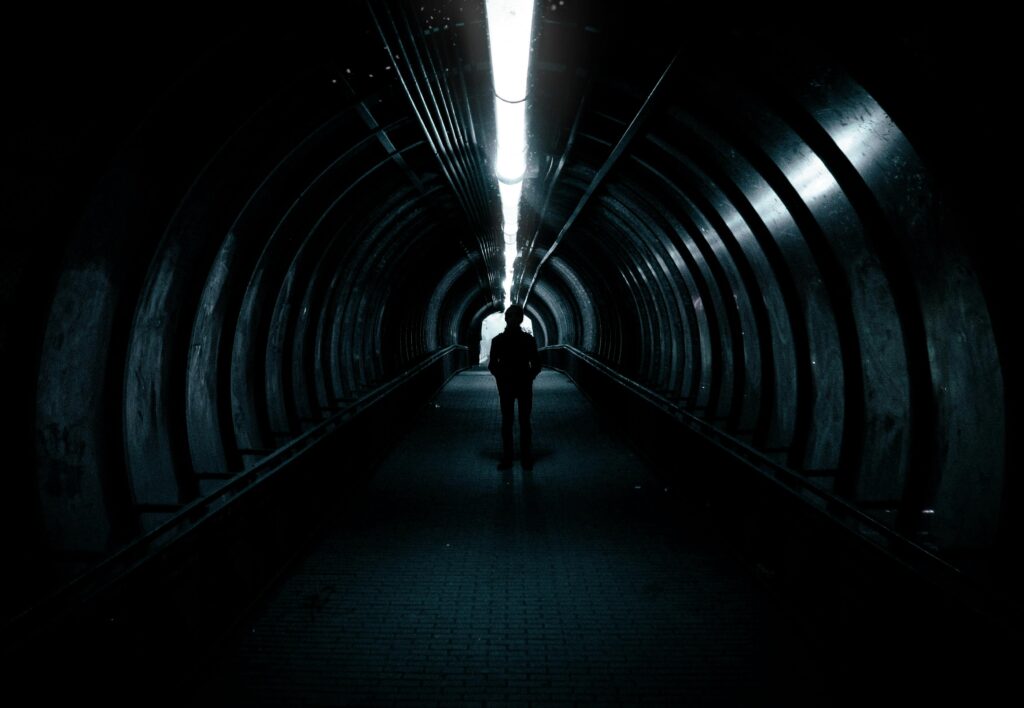 A person going down a long tunnel with a light at the end symbolising a journey