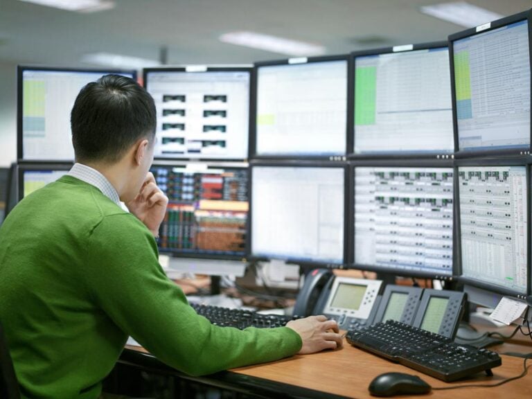 Man analysing financial data on multiple monitors