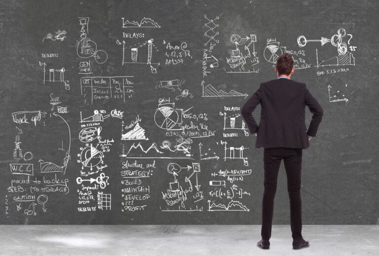 Businessman analysing business growth strategy diagrams on chalkboard