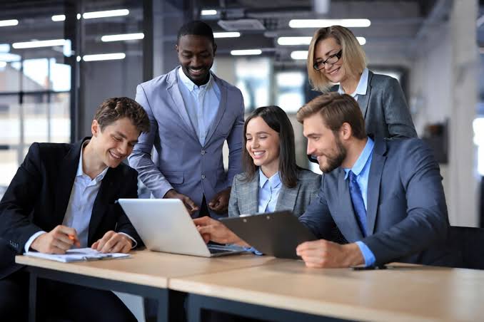 Five colleagues collaborating around laptop in office
